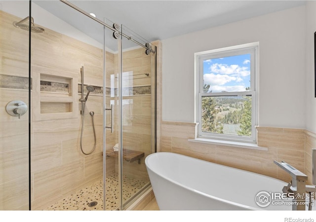 880 Hummer Dr, Nederland, CO 80466 - full bath featuring a soaking tub, a stall shower, tile walls, and wainscoting
