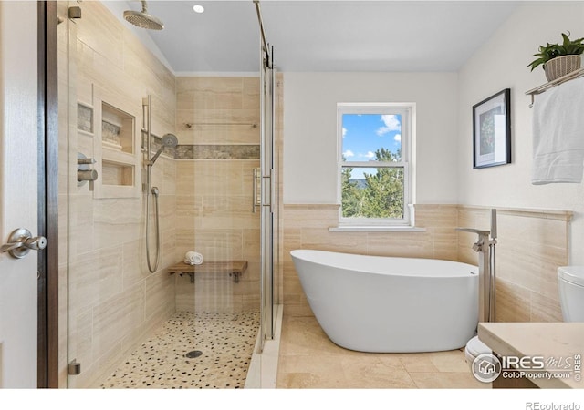 880 Hummer Dr, Nederland, CO 80466 - bathroom with a shower stall, a soaking tub, tile walls, wainscoting, and tile patterned floors