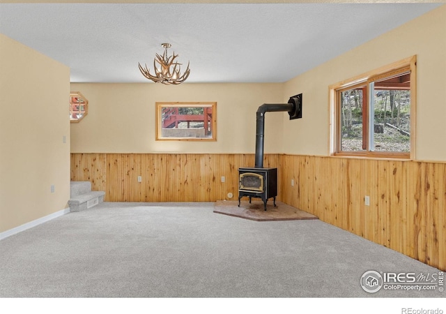880 Hummer Dr, Nederland, CO 80466 - unfurnished room with wainscoting, a wood stove, carpet, stairs, and wood walls