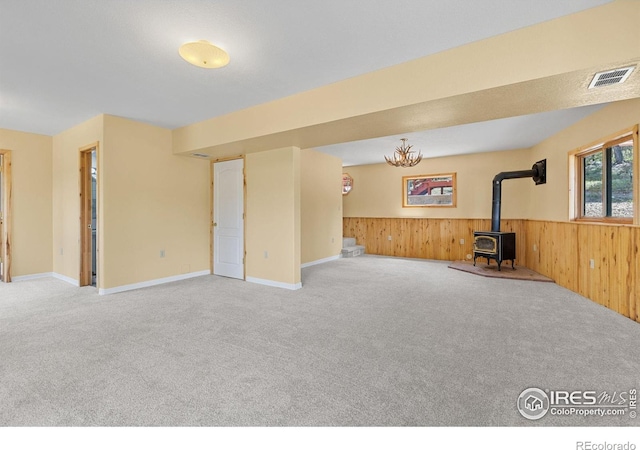 880 Hummer Dr, Nederland, CO 80466 - unfurnished living room with a wood stove, carpet flooring, wood walls, and wainscoting