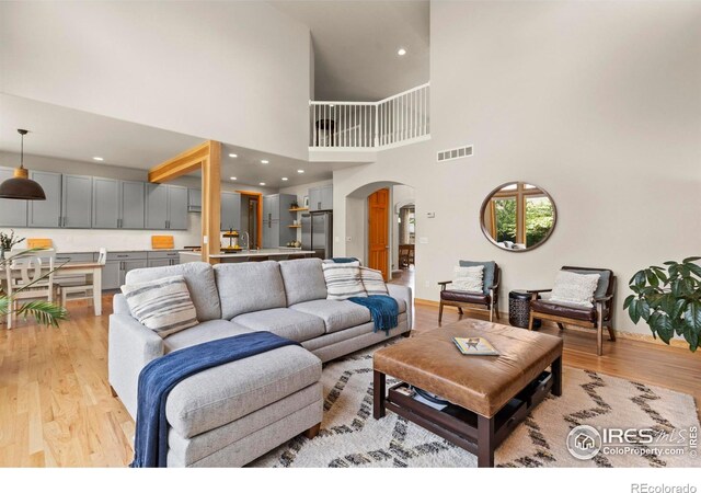 5751 Round Rock Ct, Fort Collins, CO 80528 - living area featuring arched walkways, light wood finished floors, a towering ceiling, baseboards, and recessed lighting