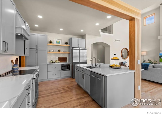 5751 Round Rock Ct, Fort Collins, CO 80528 - kitchen with appliances with stainless steel finishes, a sink, gray cabinetry, arched walkways, and tasteful backsplash