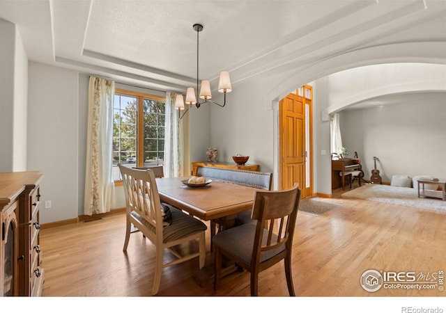 5751 Round Rock Ct, Fort Collins, CO 80528 - dining area featuring arched walkways, a chandelier, light wood-type flooring, and baseboards