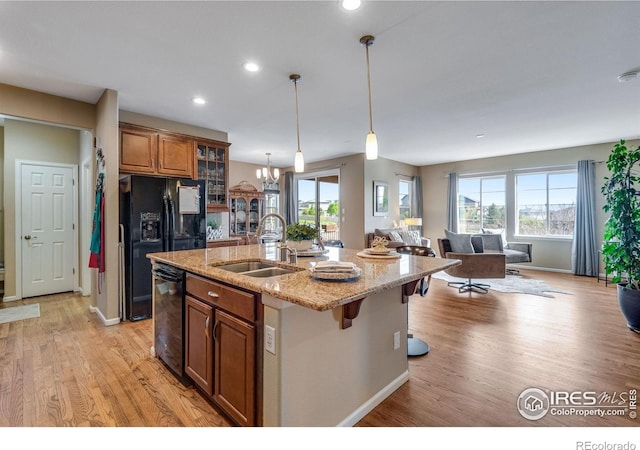 4000 Donnington Cir, Castle Rock, CO 80104 - kitchen with a sink, brown cabinets, black appliances, a center island with sink, and light wood-type flooring