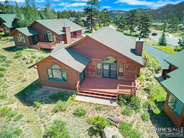683 Cedar Ridge Cir, Estes Park, CO 80517 - rear view of property featuring a deck, a shingled roof, and a chimney