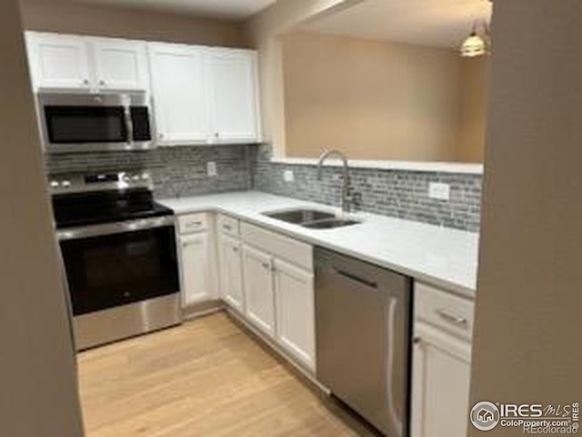 2218 Stetson Creek Dr Unit C, Fort Collins, CO 80528 - kitchen featuring appliances with stainless steel finishes, a sink, white cabinetry, light wood-type flooring, and light countertops