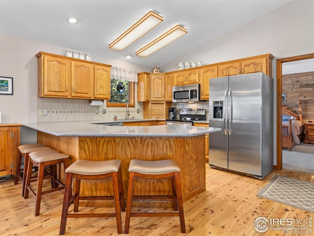 3807 Dollar Lake Dr, Estes Park, CO 80517 - kitchen with stainless steel appliances, a peninsula, vaulted ceiling, decorative backsplash, and a kitchen breakfast bar