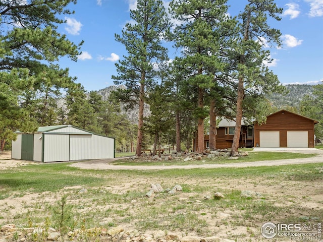 3807 Dollar Lake Dr, Estes Park, CO 80517 - view of green lawn featuring an outbuilding, dirt driveway, and an attached garage