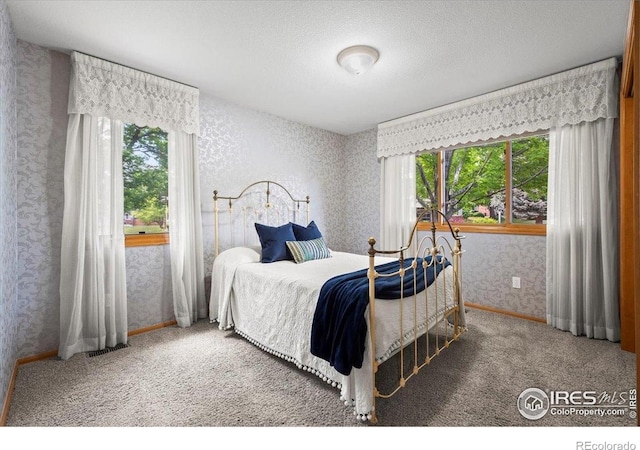 1528 16th Pl, Longmont, CO 80501 - carpeted bedroom featuring wallpapered walls, multiple windows, a textured ceiling, and baseboards