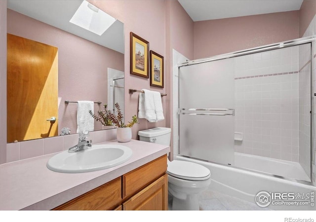 1528 16th Pl, Longmont, CO 80501 - bathroom featuring a skylight, toilet, vanity, bath / shower combo with glass door, and tile patterned flooring