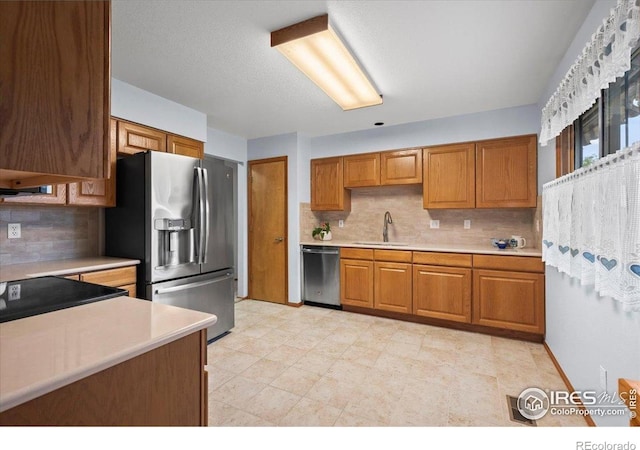 1528 16th Pl, Longmont, CO 80501 - kitchen with stainless steel appliances, a sink, light countertops, brown cabinets, and tasteful backsplash