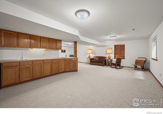 1528 16th Pl, Longmont, CO 80501 - kitchen featuring brown cabinets, open floor plan, a sink, light countertops, and light colored carpet