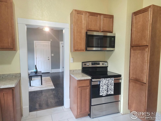 936 E 4th St, Loveland, CO 80537 - kitchen with stainless steel appliances, brown cabinets, ceiling fan, and light tile patterned floors