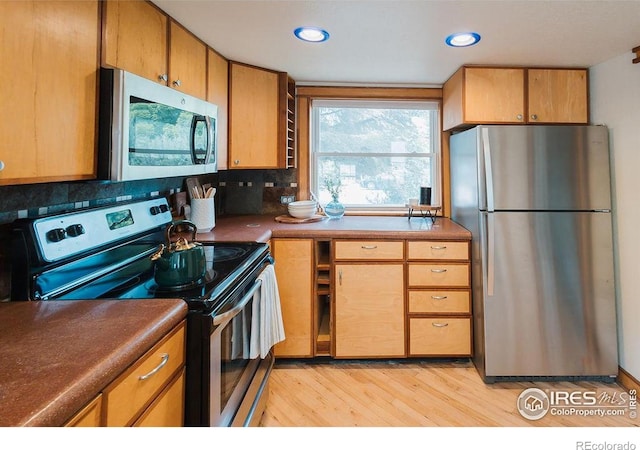 1155 Monroe Ave, Loveland, CO 80537 - kitchen featuring appliances with stainless steel finishes, light wood finished floors, tasteful backsplash, recessed lighting, and dark countertops