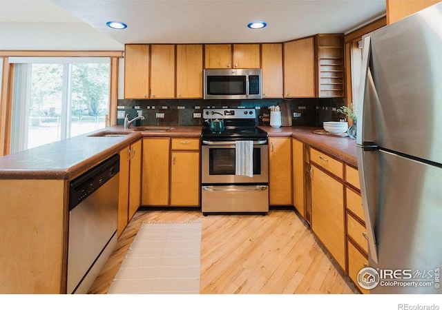 1155 Monroe Ave, Loveland, CO 80537 - kitchen with stainless steel appliances, tasteful backsplash, light wood-style flooring, dark countertops, and recessed lighting