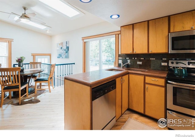 1155 Monroe Ave, Loveland, CO 80537 - kitchen featuring stainless steel appliances, decorative backsplash, vaulted ceiling, light wood-style floors, and a sink