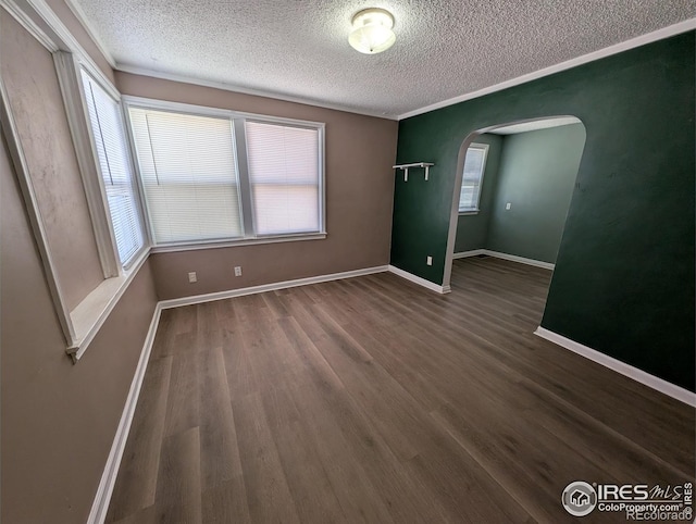 525 Jackson St, Sterling, CO 80751 - spare room featuring a textured ceiling, arched walkways, wood finished floors, and baseboards