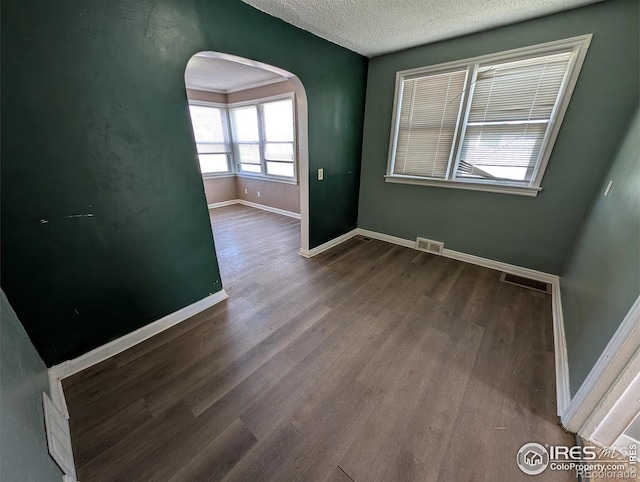525 Jackson St, Sterling, CO 80751 - empty room with arched walkways, baseboards, a textured ceiling, and wood finished floors