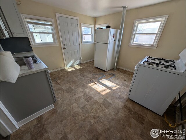 525 Jackson St, Sterling, CO 80751 - kitchen featuring white appliances, light countertops, baseboards, and stone finish floors