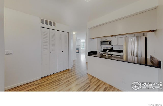 6110 Habitat Dr Unit 2, Boulder, CO 80301 - kitchen with appliances with stainless steel finishes, dark countertops, light wood-style flooring, and a peninsula