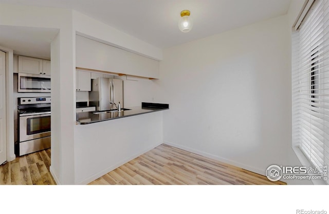 6110 Habitat Dr Unit 2, Boulder, CO 80301 - kitchen featuring appliances with stainless steel finishes, dark countertops, a sink, light wood-style flooring, and baseboards