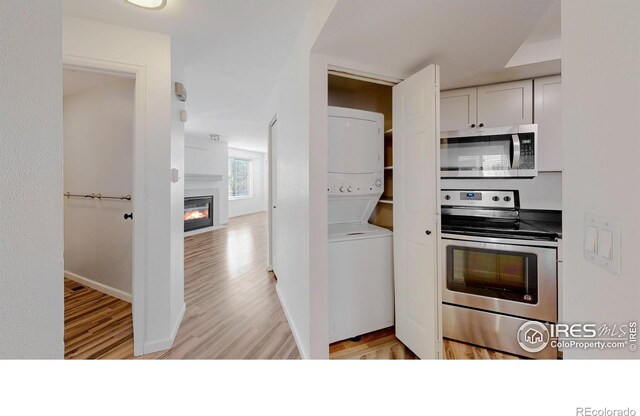 6110 Habitat Dr Unit 2, Boulder, CO 80301 - kitchen featuring stainless steel appliances, estacked washer and dryer, light wood-type flooring, and a glass covered fireplace