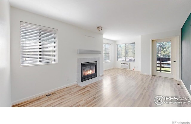 6110 Habitat Dr Unit 2, Boulder, CO 80301 - unfurnished living room with a tile fireplace, wood finished floors, an AC wall unit, and baseboards