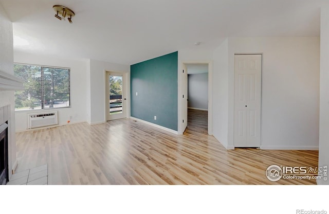 6110 Habitat Dr Unit 2, Boulder, CO 80301 - unfurnished living room featuring a tiled fireplace, a wall unit AC, wood finished floors, and baseboards