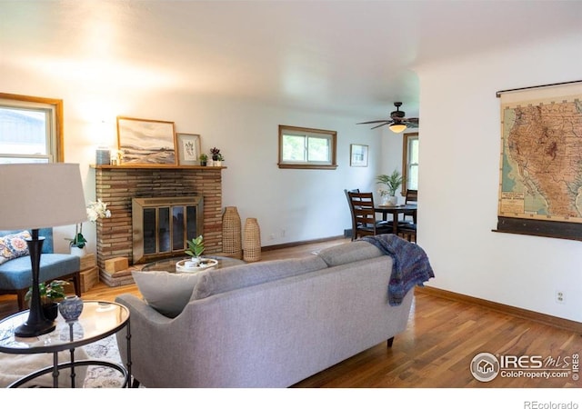 508 W 11th St, Loveland, CO 80537 - living room featuring a ceiling fan, wood finished floors, a brick fireplace, and baseboards