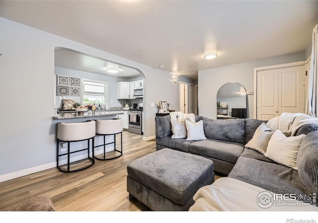 3245 W Walsh Pl, Denver, CO 80219 - living area with arched walkways, light wood finished floors, and baseboards