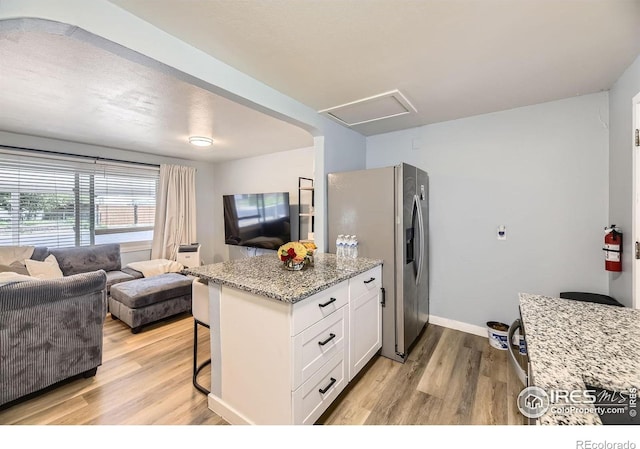 3245 W Walsh Pl, Denver, CO 80219 - kitchen with stainless steel refrigerator with ice dispenser, light wood finished floors, white cabinets, and light stone countertops