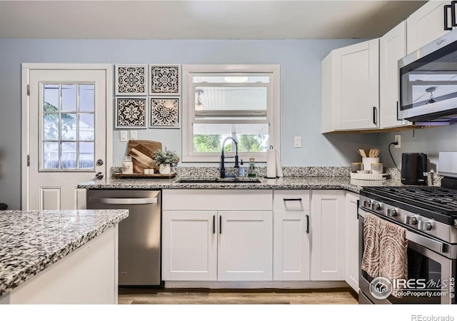 3245 W Walsh Pl, Denver, CO 80219 - kitchen with stainless steel appliances, a sink, light stone counters, and white cabinets