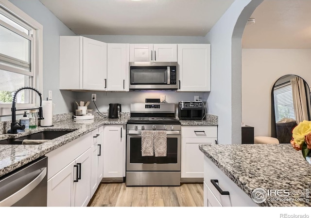 3245 W Walsh Pl, Denver, CO 80219 - kitchen featuring stainless steel appliances, a sink, light wood-style floors, light stone counters, and white cabinets