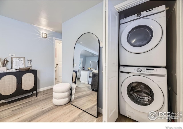 3245 W Walsh Pl, Denver, CO 80219 - washroom with estacked washer and dryer, light wood-style floors, arched walkways, and baseboards