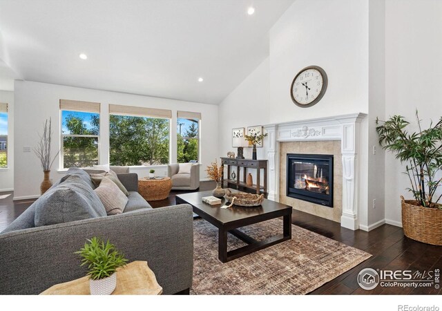 6614 Neota Creek Ct, Timnath, CO 80547 - living area with a tiled fireplace, dark wood-type flooring, recessed lighting, high vaulted ceiling, and baseboards