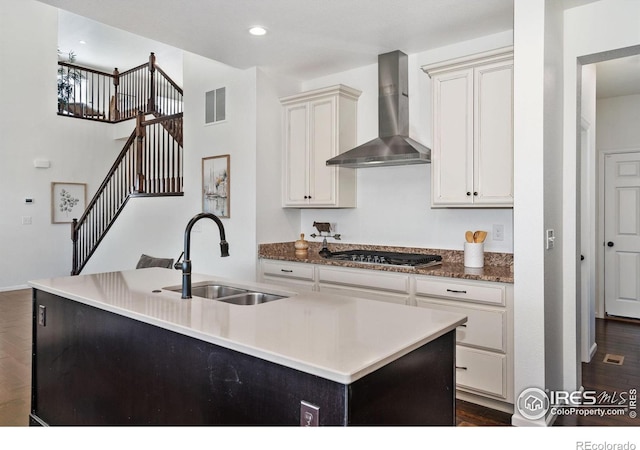 6614 Neota Creek Ct, Timnath, CO 80547 - kitchen featuring wall chimney exhaust hood, a sink, stainless steel gas stovetop, dark wood finished floors, and an island with sink