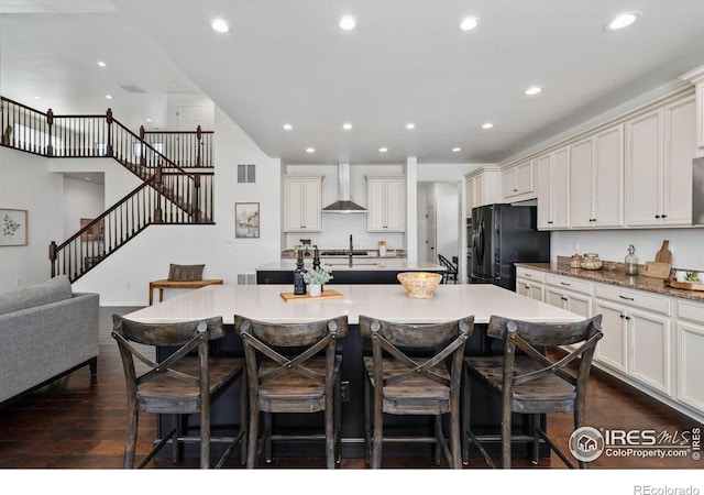 6614 Neota Creek Ct, Timnath, CO 80547 - kitchen featuring wall chimney exhaust hood, freestanding refrigerator, a kitchen island with sink, a breakfast bar, and recessed lighting
