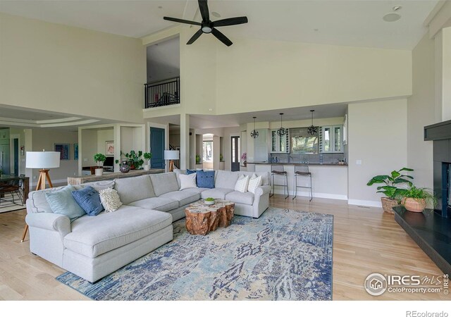 7205 Rustic Trl, Boulder, CO 80301 - living room featuring a ceiling fan, high vaulted ceiling, light wood-type flooring, baseboards, and a fireplace with raised hearth