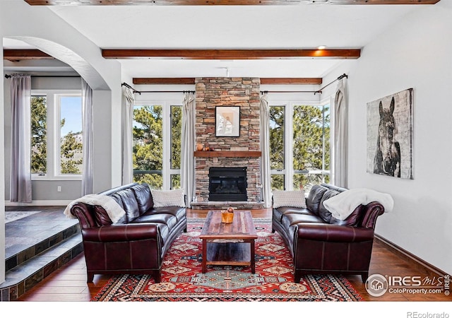 290 Skyhill Dr, Evergreen, CO 80439 - living area featuring beam ceiling, wood finished floors, baseboards, a stone fireplace, and arched walkways