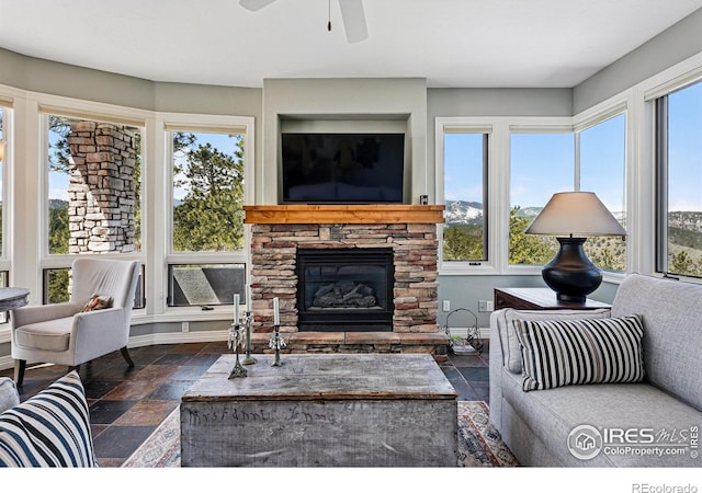 290 Skyhill Dr, Evergreen, CO 80439 - living room featuring stone tile floors, ceiling fan, a stone fireplace, and baseboards
