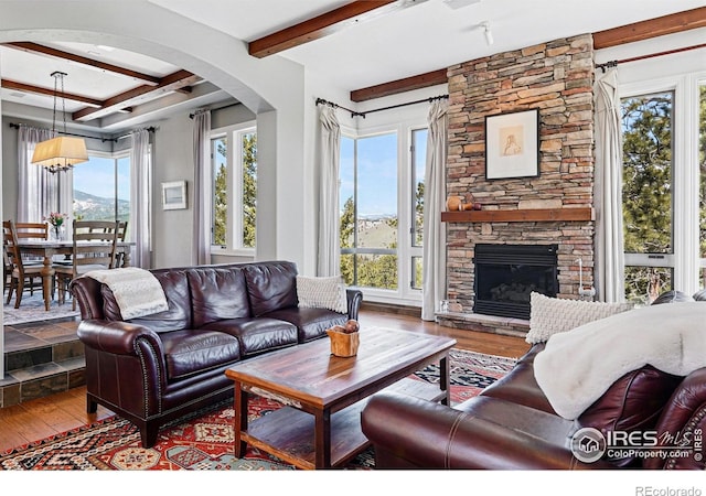 290 Skyhill Dr, Evergreen, CO 80439 - living area with beamed ceiling, hardwood / wood-style flooring, arched walkways, and a fireplace