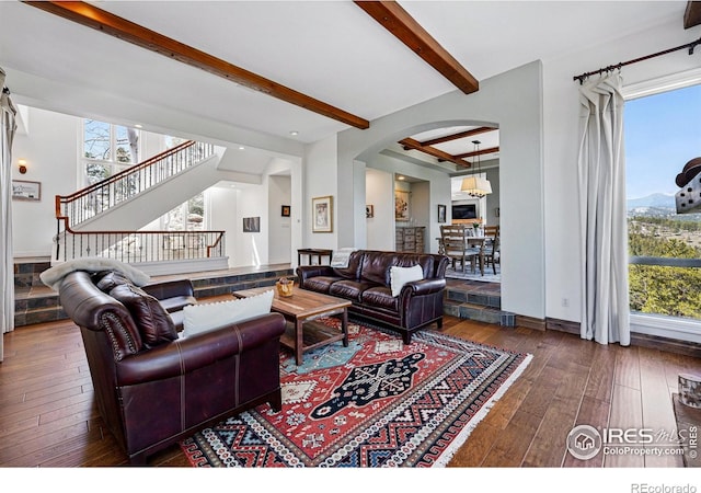 290 Skyhill Dr, Evergreen, CO 80439 - living room featuring arched walkways, hardwood / wood-style floors, beam ceiling, healthy amount of natural light, and stairway