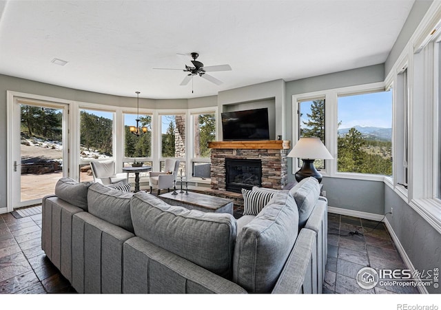 290 Skyhill Dr, Evergreen, CO 80439 - living area with stone tile flooring, baseboards, a stone fireplace, and a ceiling fan