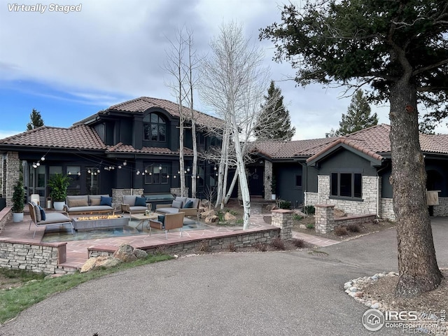 290 Skyhill Dr, Evergreen, CO 80439 - view of front of property featuring an outdoor living space with a fire pit, a tile roof, a patio, stone siding, and stucco siding