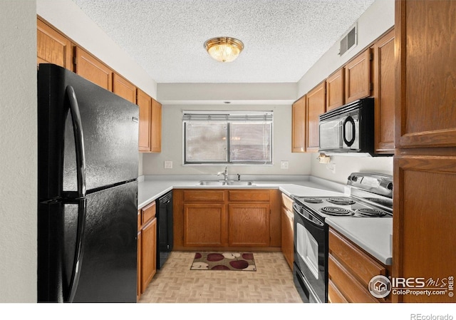 316 Wright St Unit 203, Lakewood, CO 80228 - kitchen featuring black appliances, a sink, brown cabinets, light countertops, and a textured ceiling