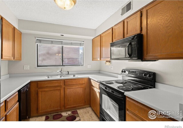 316 Wright St Unit 203, Lakewood, CO 80228 - kitchen with black appliances, a sink, a textured ceiling, light countertops, and brown cabinetry