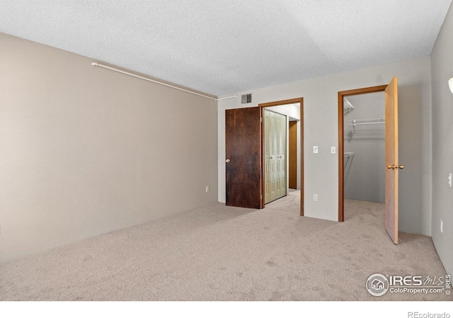 316 Wright St Unit 203, Lakewood, CO 80228 - unfurnished bedroom featuring light carpet, a walk in closet, a textured ceiling, and a closet