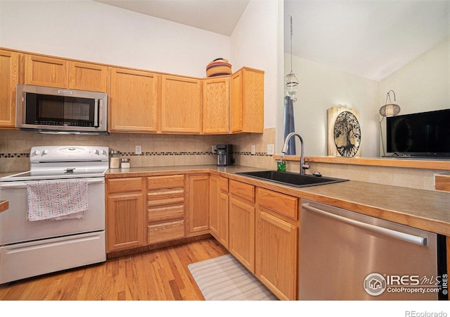 2502 Ballard Ln, Fort Collins, CO 80524 - kitchen with stainless steel appliances, a sink, vaulted ceiling, tasteful backsplash, and light wood finished floors