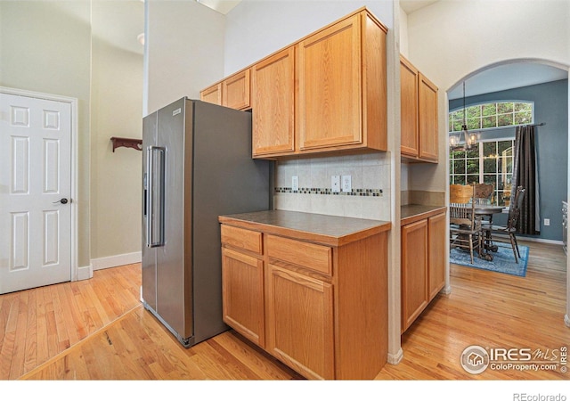 2502 Ballard Ln, Fort Collins, CO 80524 - kitchen with high quality fridge, light wood-style floors, arched walkways, backsplash, and dark countertops