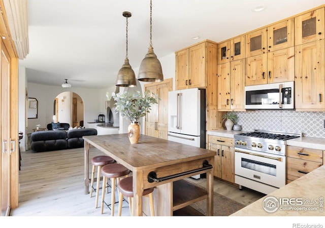 320 Elk Ln, Grand Lake, CO 80447 - kitchen featuring premium appliances, arched walkways, light wood-style floors, light brown cabinetry, and light countertops